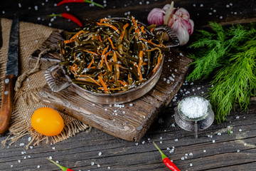 seaweed and carrot salad, mayonnaise sauce, in a rustic rustic bowl bowl, fork knife spoon, spices,...