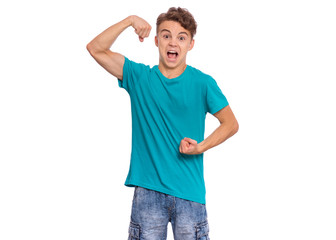 Portrait of funny teen boy raised his hands and shows biceps, isolated on white background. Handsome teenage young boy shows biceps, looking at camera in amazement. Happy strong child flexing biceps