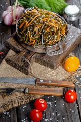 seaweed and carrot salad, mayonnaise sauce, in a rustic rustic bowl bowl, fork knife spoon, spices,...