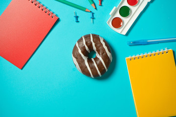 Concept wrong food at school. Charge for the brain. Chocolate donut on a blue background around the...