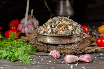 seaweed and carrot salad, mayonnaise sauce, in a rustic rustic bowl bowl, fork knife spoon, spices,...