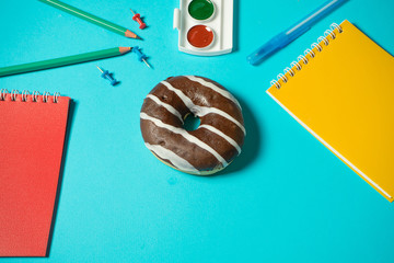 Concept wrong food at school. Charge for the brain. Chocolate donut on a blue background around the...