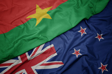 waving colorful flag of new zealand and national flag of burkina faso.
