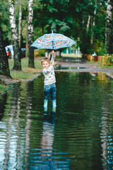Portrait of a cute little boy raising an umbrella over his head