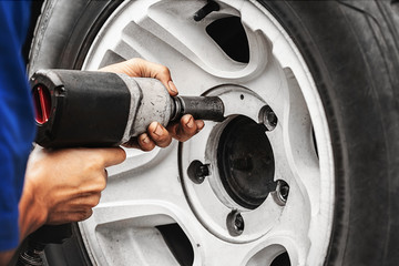 close up auto mechanic changing car wheel with tool machine