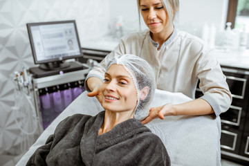 Fototapeta premium Cosmetologist carefully putting client's head on the couch before the procedure