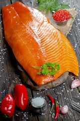 a large piece of red fish fillet with vegetables and spices and fresh herbs, stand and lie, from...