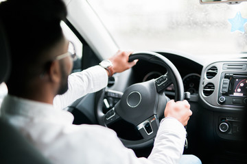 Concentrating on the road. Rear view of young handsome man looking straight while driving a car