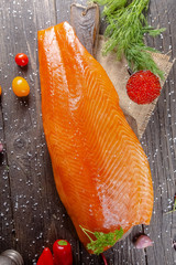 a large piece of red fish fillet with vegetables and spices and fresh herbs, stand and lie, from...