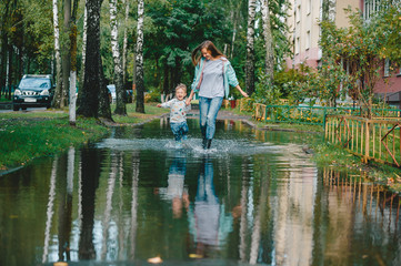 Fototapeta na wymiar Young mother with little son walking in the street after a rain.