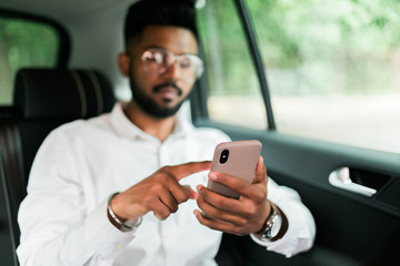 Confident and successful. Close up of young man holding his smart phone while sitting in the car