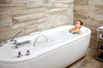 Beautiful woman relaxing in the bathtub having a hydromassage therapy in the SPA