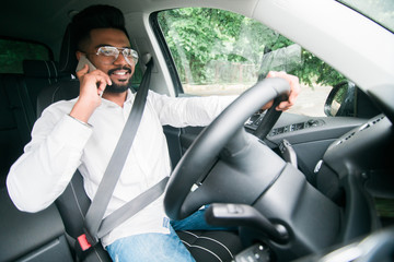 Young indian business man talking on the phone while driving his car