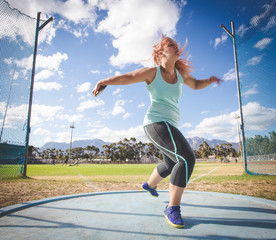 Wide angle action photo of a female discus athlete throwing a discus