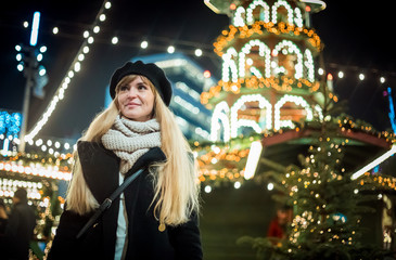 Happy smiling girl at Christmas market, illuminated bokeh background