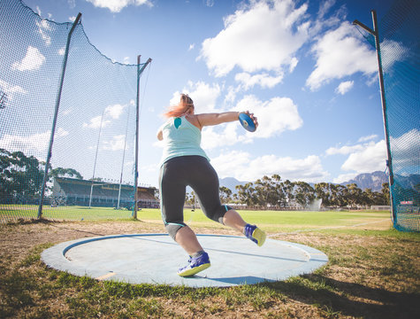 Wide angle action photo of a female discus athlete throwing a discus