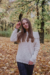 Close up portrait of a Beautiful girl in white sweater near colorful autumn leaves. Artwork of romantic woman .Pretty tenderness model smiling