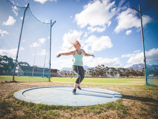 Wide angle action photo of a female discus athlete throwing a discus