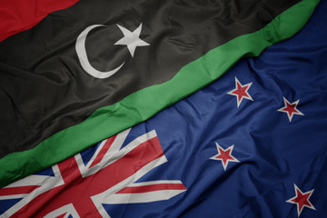 waving colorful flag of new zealand and national flag of libya.