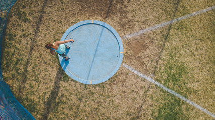 Wide angle action photo of a female discus athlete throwing a discus