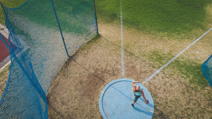 Wide angle action photo of a female discus athlete throwing a discus