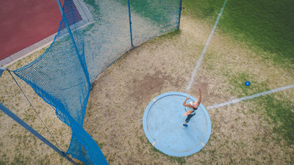 Wide angle action photo of a female discus athlete throwing a discus