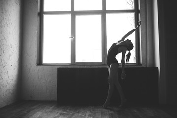Plasticity slim woman dancing near window. Professional dancer enjoy dance. Lady Dancer Training Modern Ballet In Class. Contemporary dance performer. Daylight, silhouette beautiful body. Dance theme