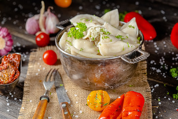 dumplings made of red and white fish meat, in a vintage rustic bowl plate, fork knife spoon, salt,...