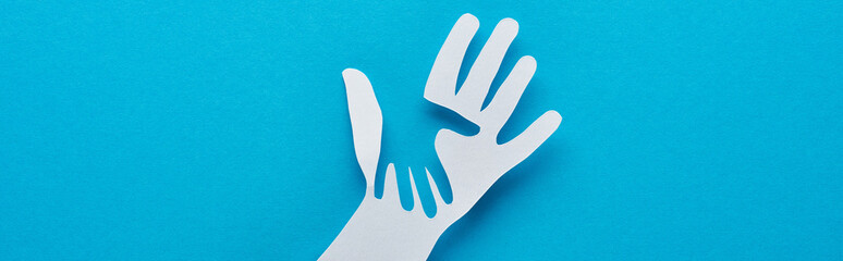 top view of paper cut parent and child hands on blue background, panoramic shot - obrazy, fototapety, plakaty