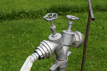 Silver fire hydrant with a hose closeup