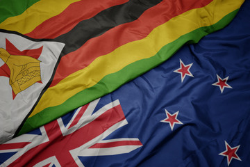 waving colorful flag of new zealand and national flag of zimbabwe.