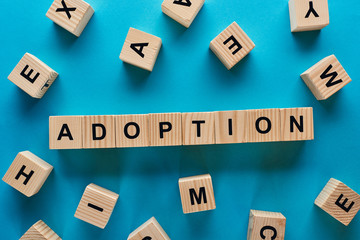 top view of adoption word made of wooden blocks on blue background