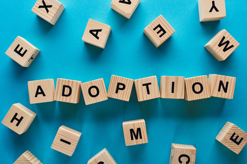 top view of adoption word made of wooden cubes on blue background