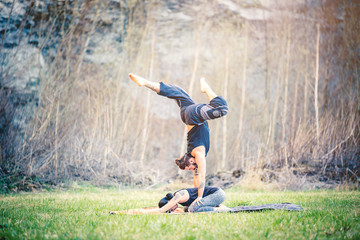  Giovane coppia pratica acroyoga e yoga all'aperto in montagna al parco
