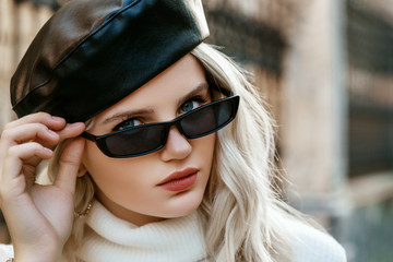 Outdoor close up street fashion portrait of  young elegant blonde woman wearing black leather...