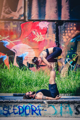 Scenario urbano con coppia di giovani che fa acroyoga e yoga