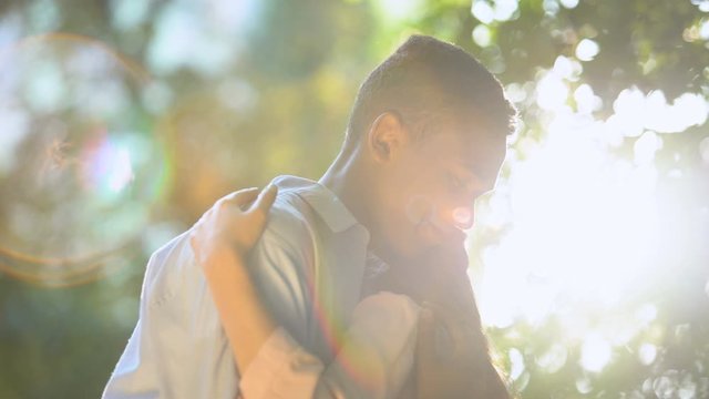Nice teenage couple in love smiling and hugging at sunny park, tenderness