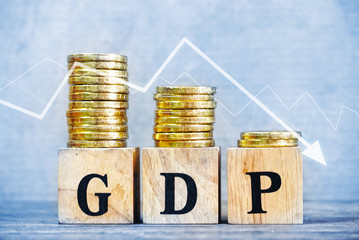 GDP text on wood cube and gold coins stack volume with trend direction down side , finance and economic concept.