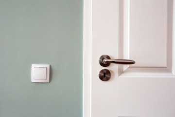 Modern white door with chrome door handle and light switch, new clean design - obrazy, fototapety, plakaty
