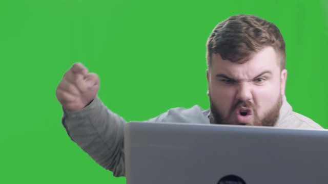 Angry business man talking laptop at green scren background. Portrait of Angry professional have conversation on laptop. Chroma key. 4k