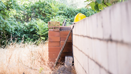 building plot detail with half built wall and bricks and yellow helmet