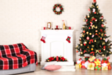 Blurred background of fireplace near sofa and christmas tree