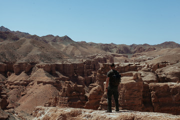 Man stands in front of rocks at canyon