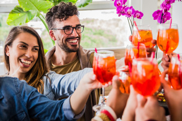 Group of young friends toasting with cocktails having fun at a weekend party