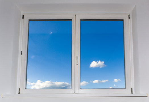 View of closed white window overlooking blue sky with clouds, view from home