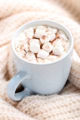 Cappuccino with marshmallows in cup and knitted scarf