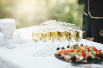 Glasses of champagne and snacks on the table at the event outdoors, catering