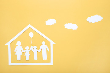 Paper family figures with clouds and house on yellow background