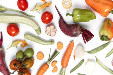 Creative layout made of vegetables. Healthy eating concept. Tomatoes, onion, carrot, garlic, red beet, pepper, maize and green haricot on white background. Flat lay, top view, copy space