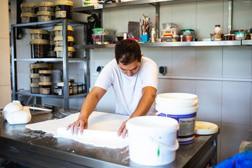 A man decorates and makes cakes in a pastry shop
